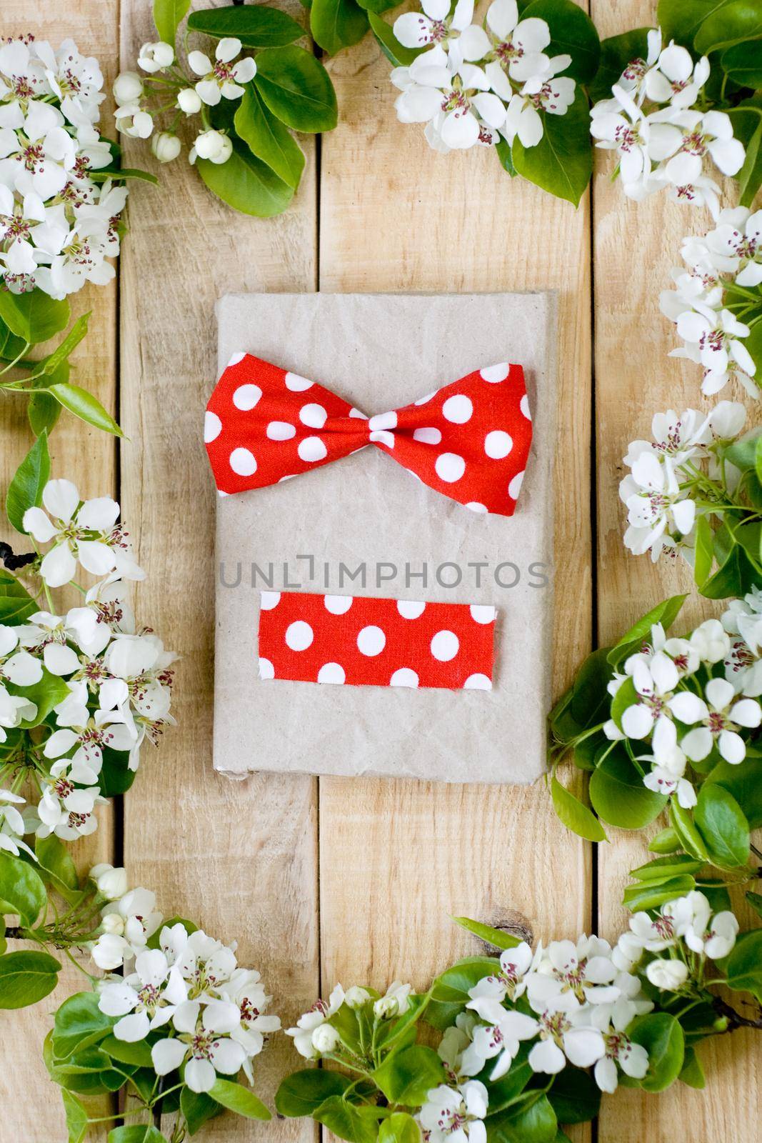 Natural wooden background with white flowers fruit tree. In the middle is a vintage notebook with bow tie