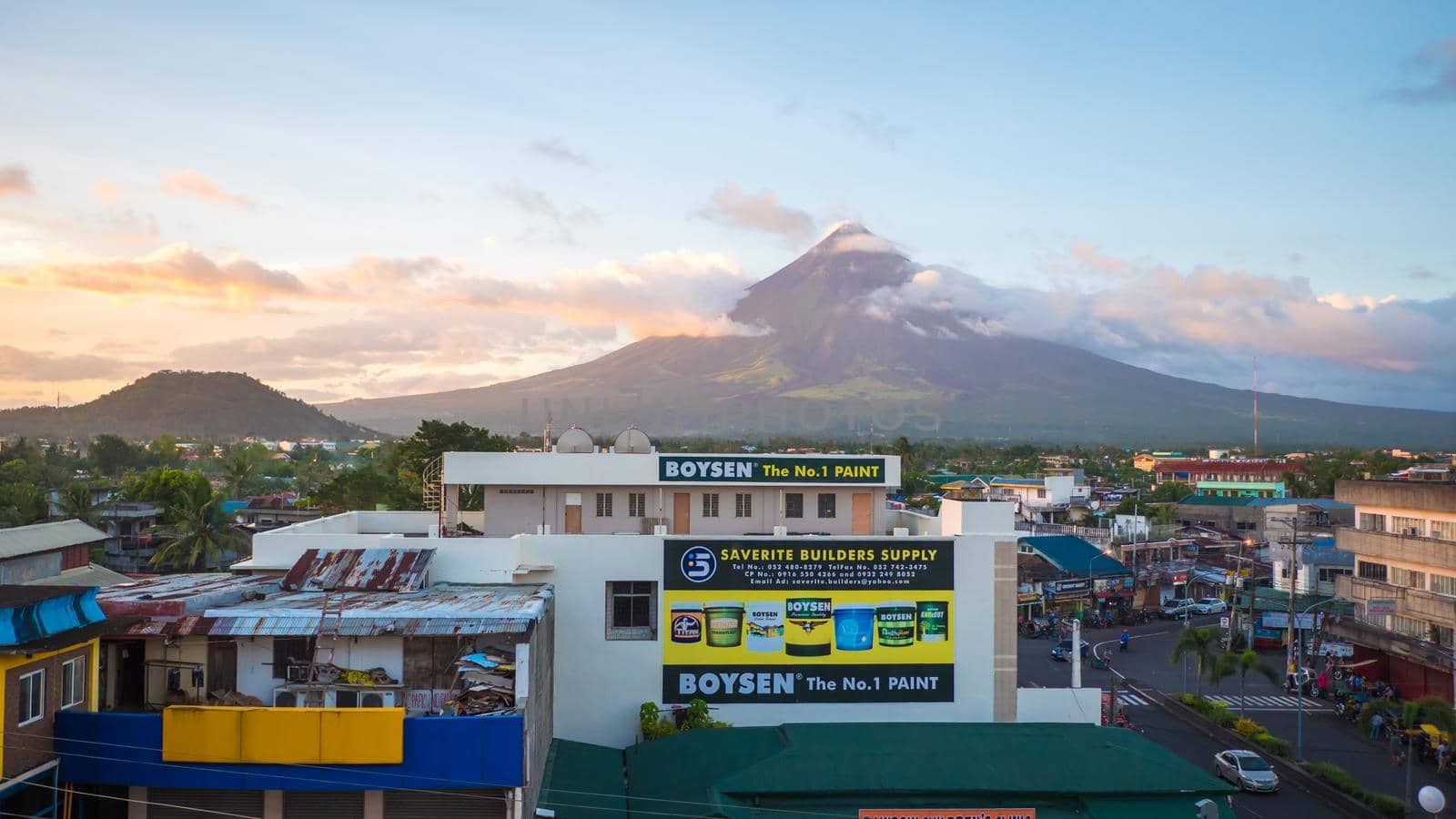LEGAZPI, PHILIPPINES - JANUARY 5, 2018: - Mount Mayon volcano looms over the city as daily life goes on. by DovidPro