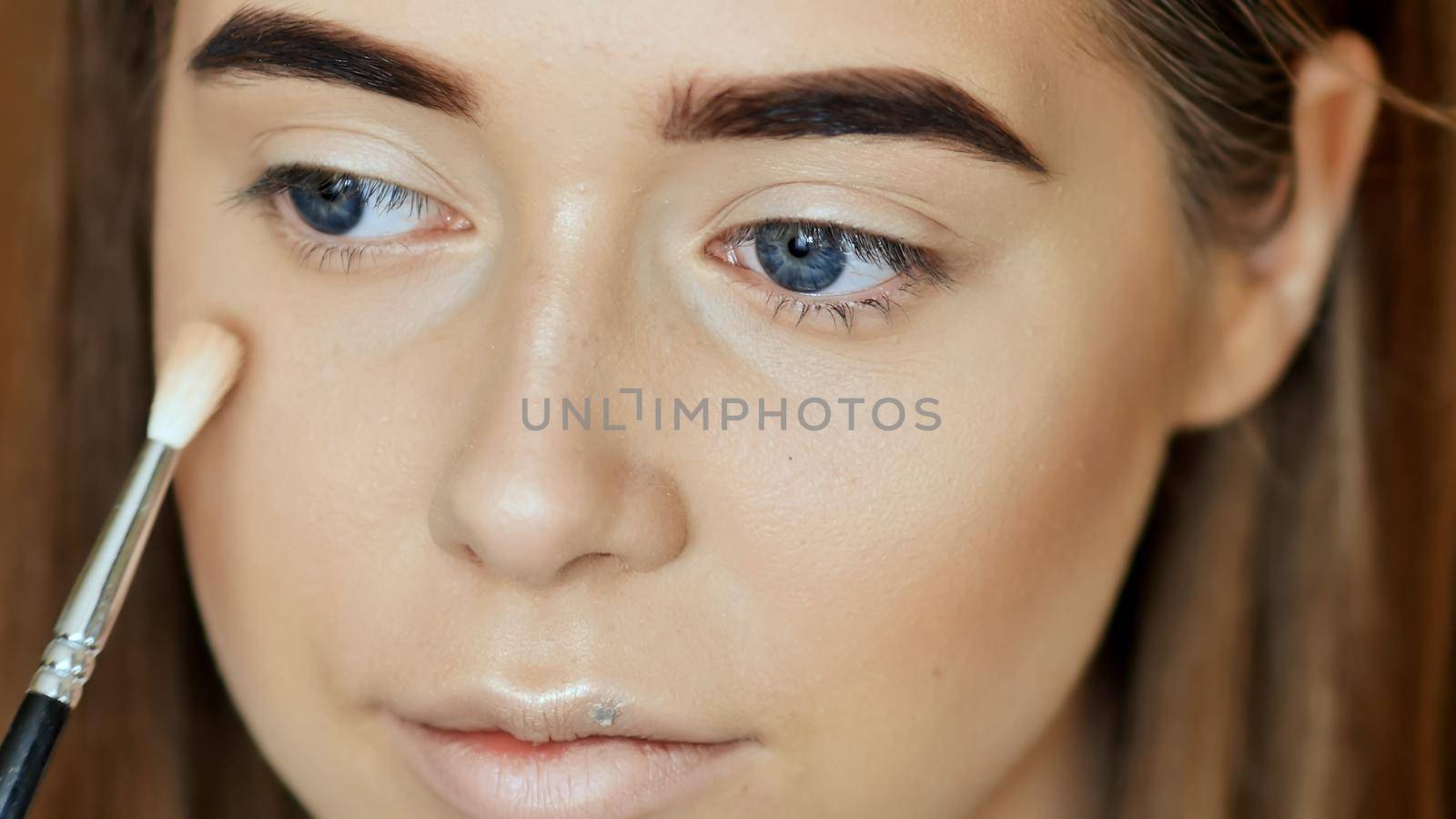 Makeup Face. Girl make-up artist treats face powder.