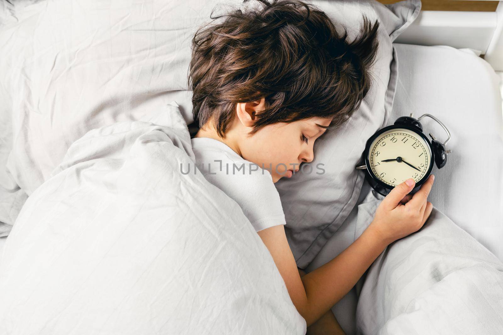 Boy sleeping after turning off his alarm clock by Syvanych