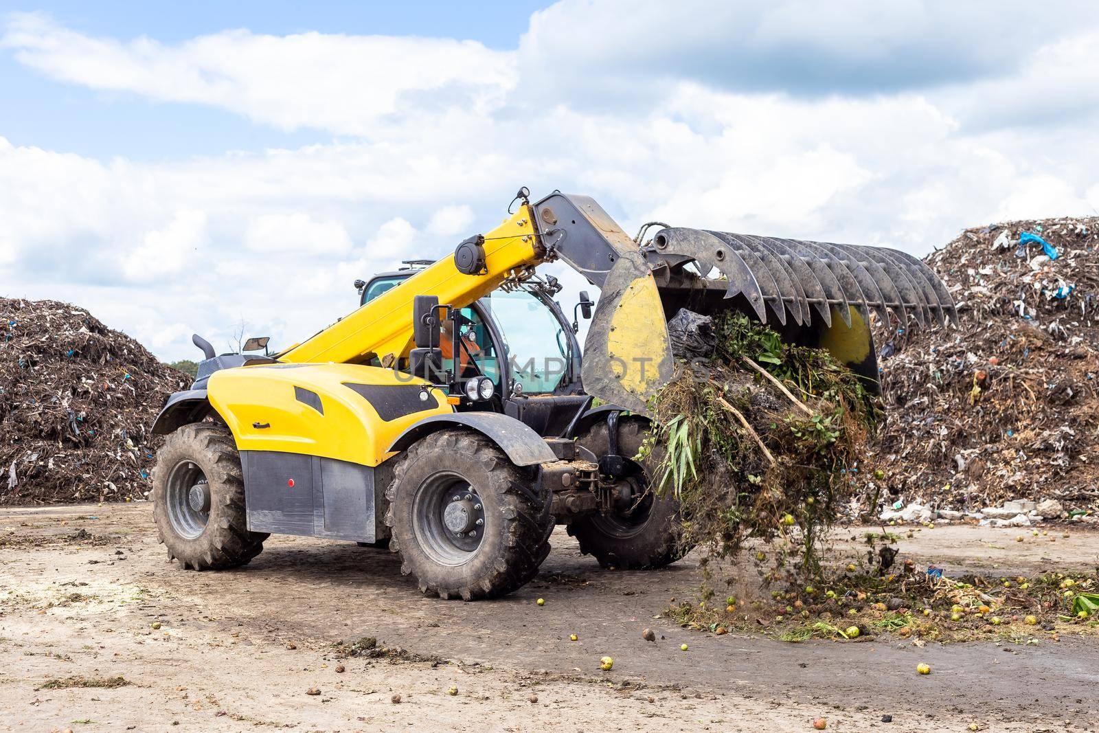 Bulldozer moving organic waste at compost recycling plant. Earth mover working on pile of compost in industrial facility