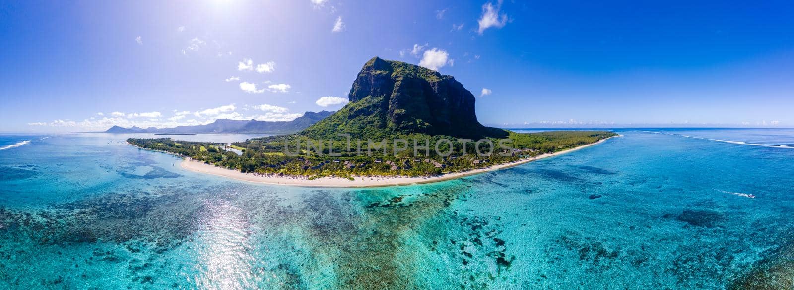 Le Morne beach Mauritius,Tropical beach with palm trees and white sand blue ocean and beach beds with umbrella,Sun chairs and parasol under a palm tree at a tropical beac, Le Morne beach Mauritius by fokkebok