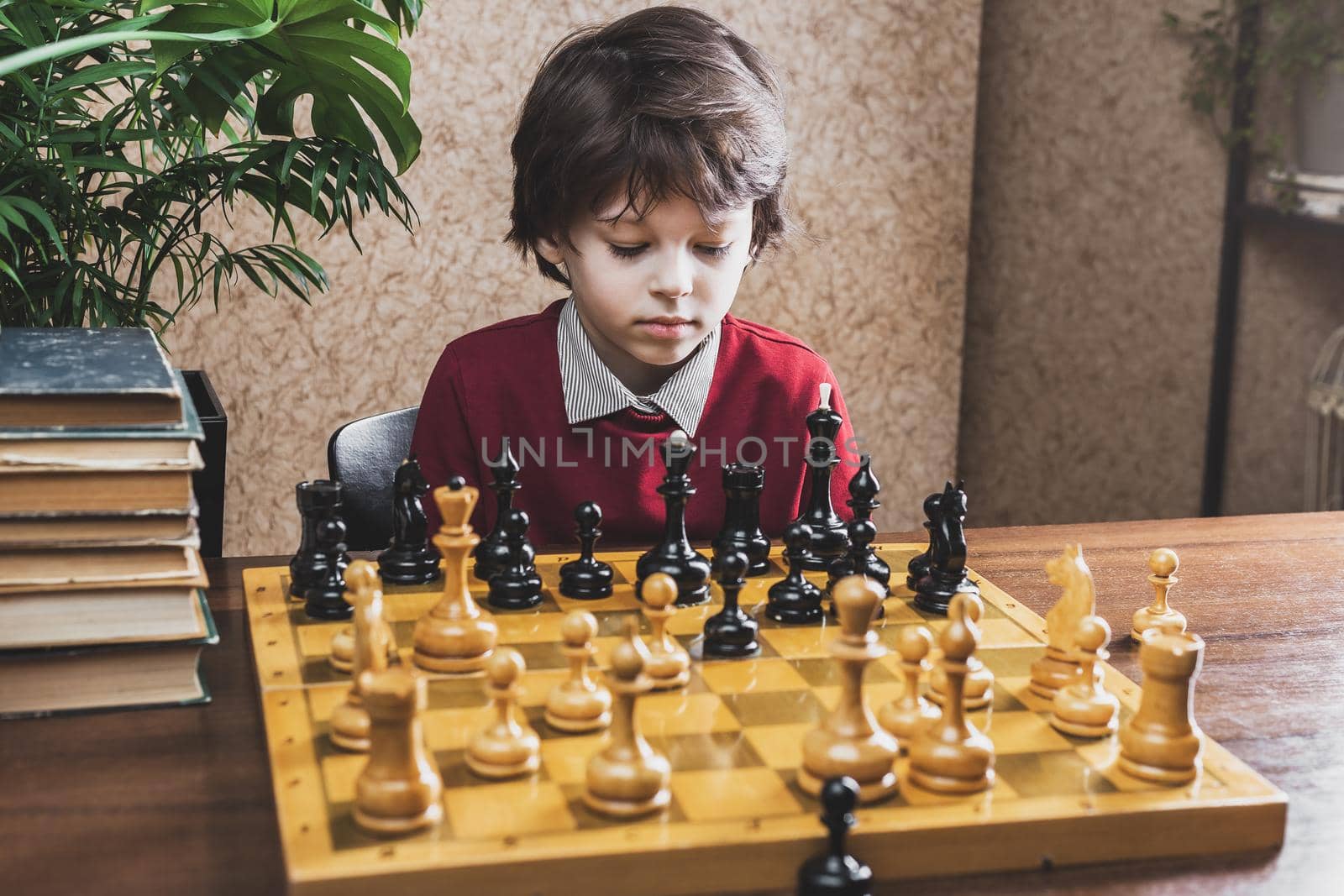 Close up of a pensive Boy pondering on next move playing chess with himself at home 