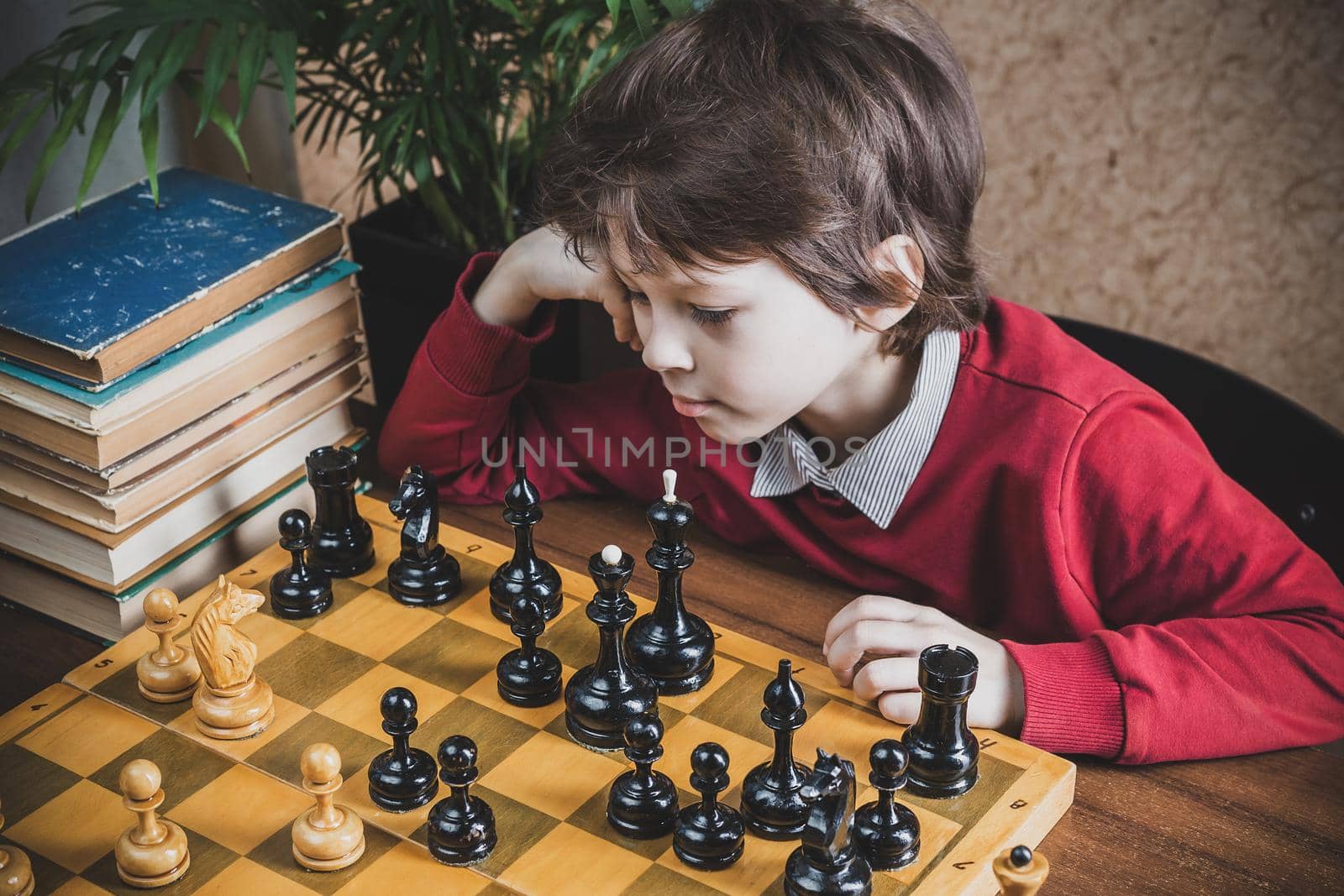 Thoughtful six years old chess player. Boy playing chess with himself at home 