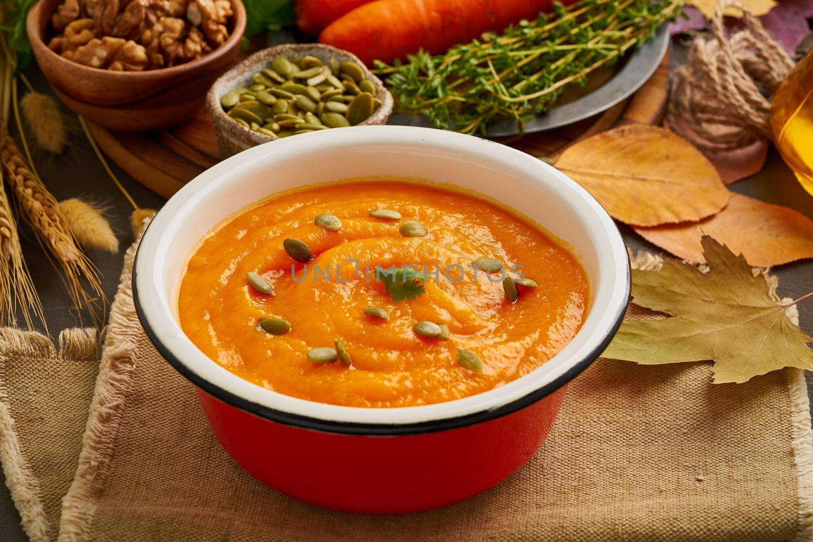 autumn dish for vegetarians, pumpkin cream soup with nuts and seeds, carrot, healthy lunch