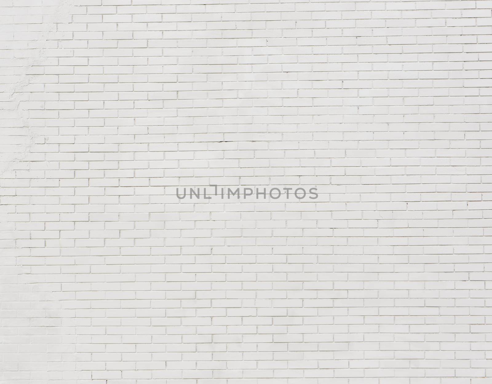 Painted brick wall and weathered sidewalk .