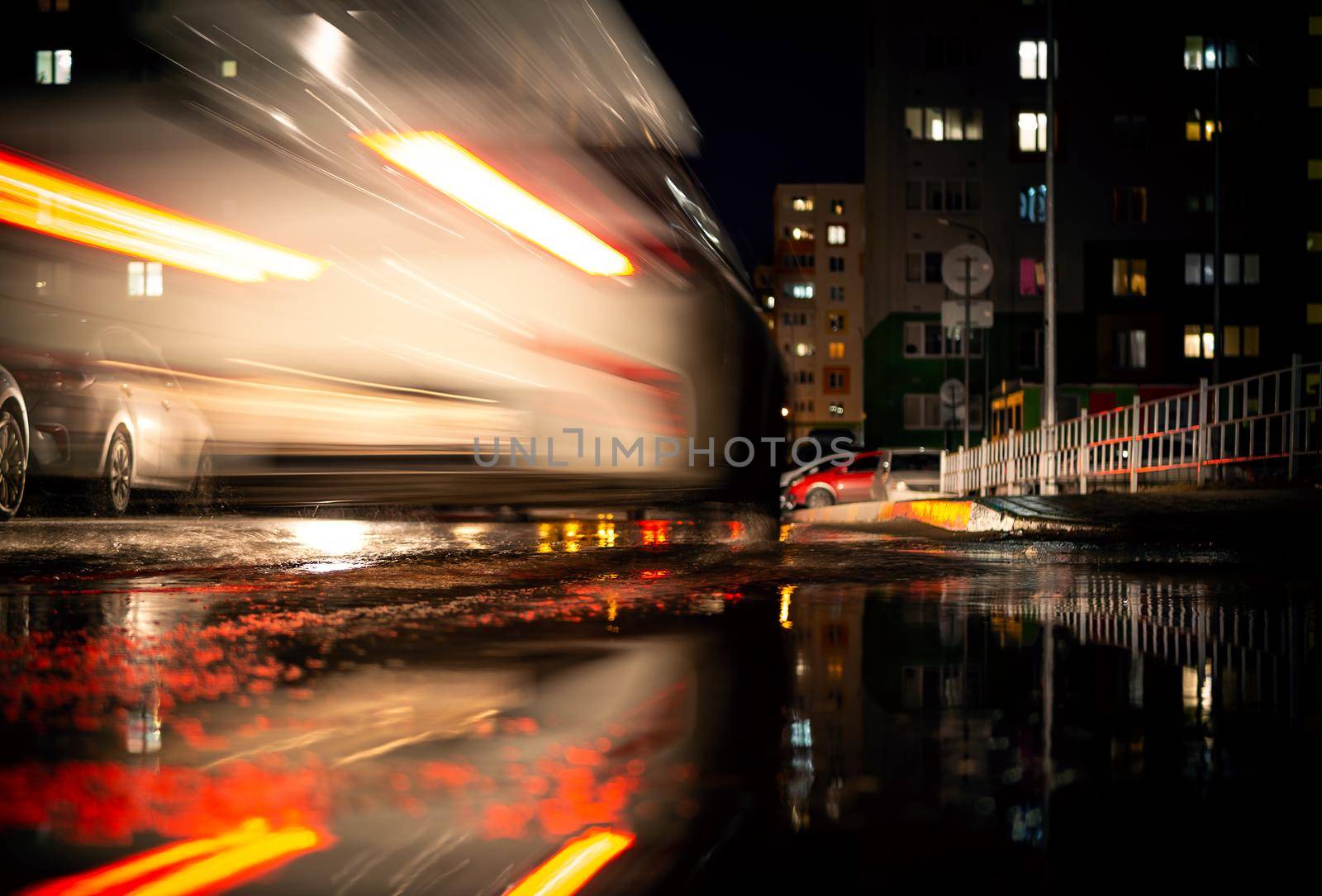 a white car on the road with a blurred traffic background. Lower camera angle, on a city street.