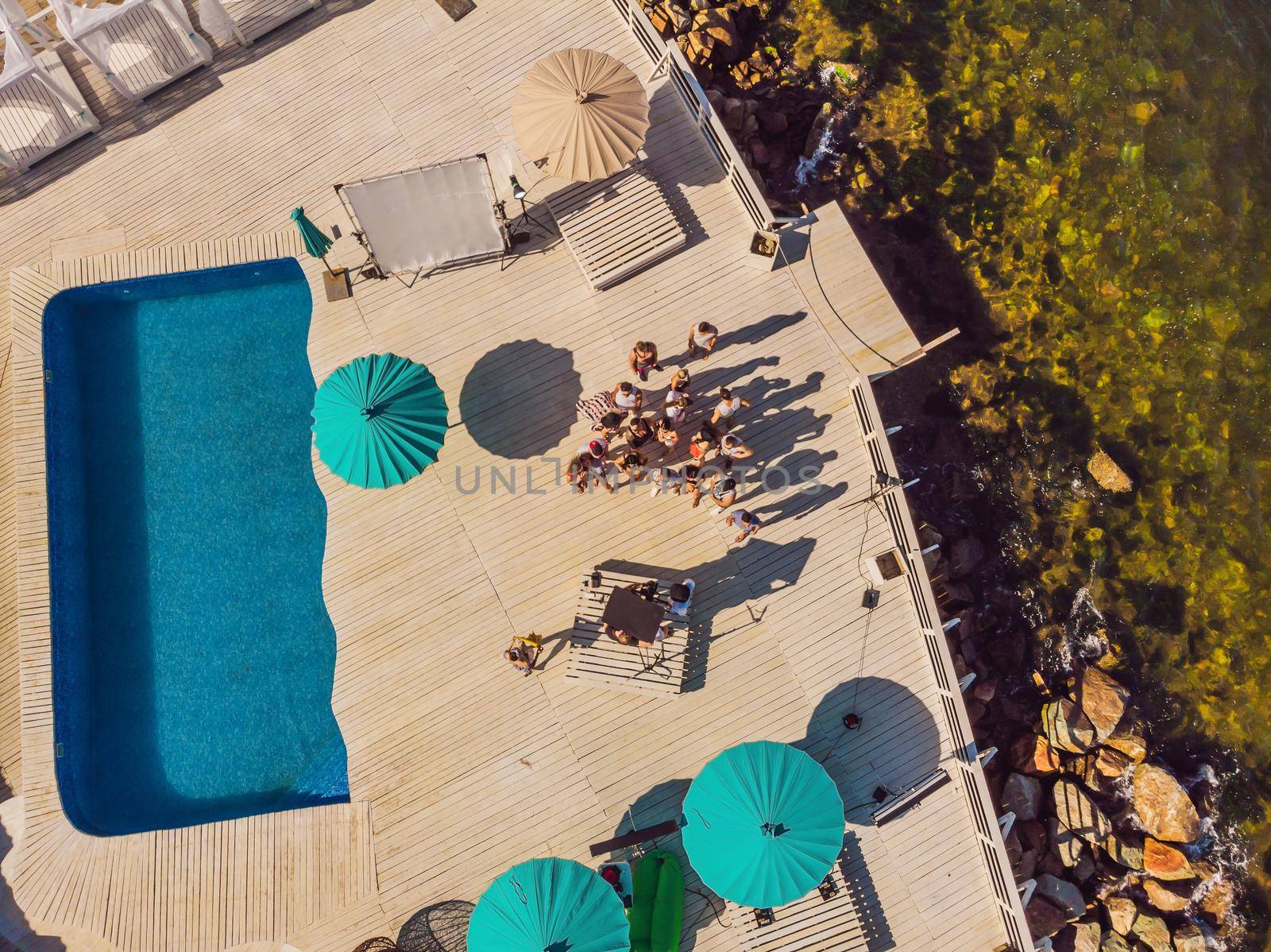 Aerial shot of the production team on a commercial video shoot. Steadicam operator uses the 3-axis camera stabilizer and cinema-grade camera. Shooting a video clip for a music group.