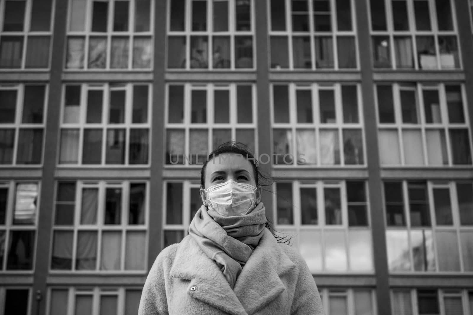 Shot of a girl in wearing face mask for protection, on the street. Against the background of a residential building with windows. lockdown Covid-19 pandemic.