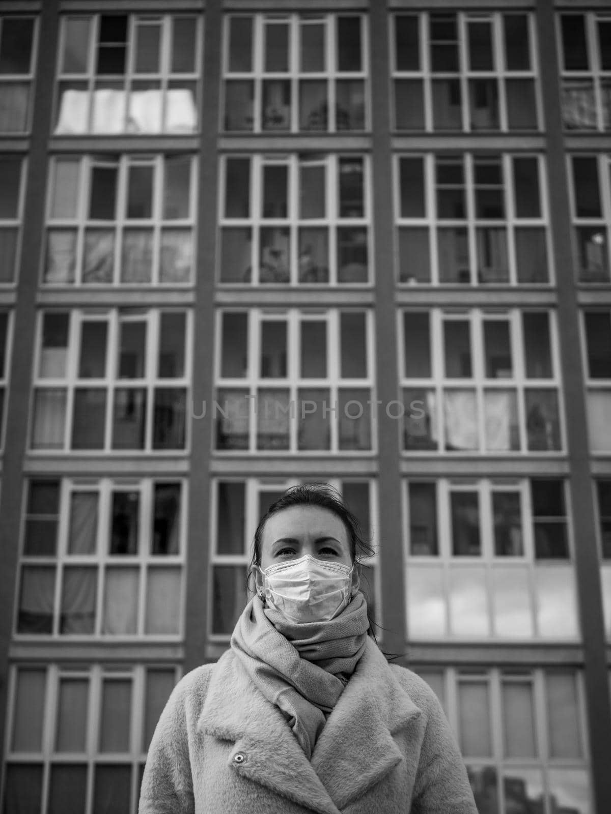 Shot of a girl in wearing face mask for protection, on the street. Against the background of a residential building with windows. lockdown Covid-19 pandemic.