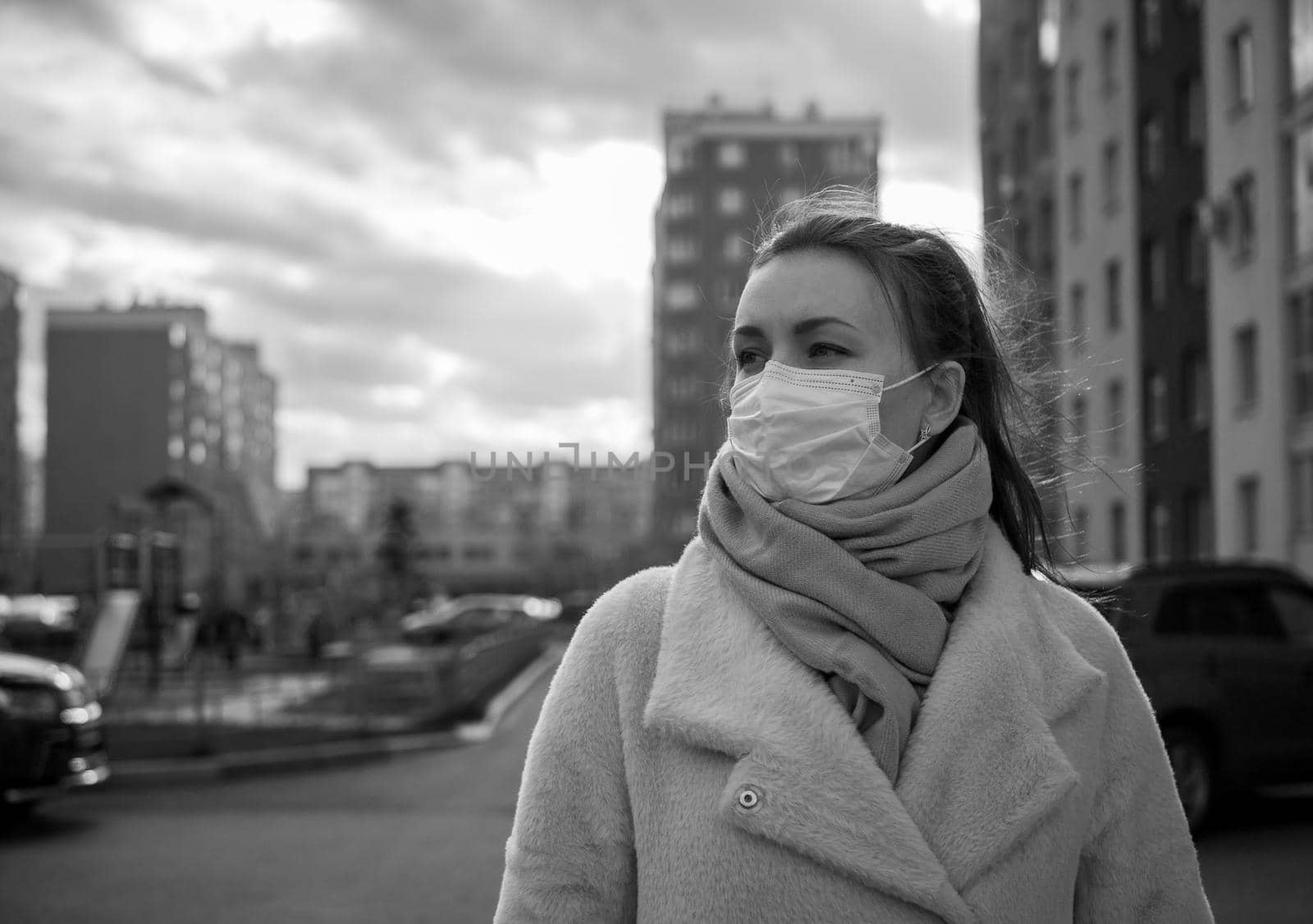 Shot of a girl in wearing face mask for protection, on the street. Against the background of a residential building with windows. lockdown Covid-19 pandemic.