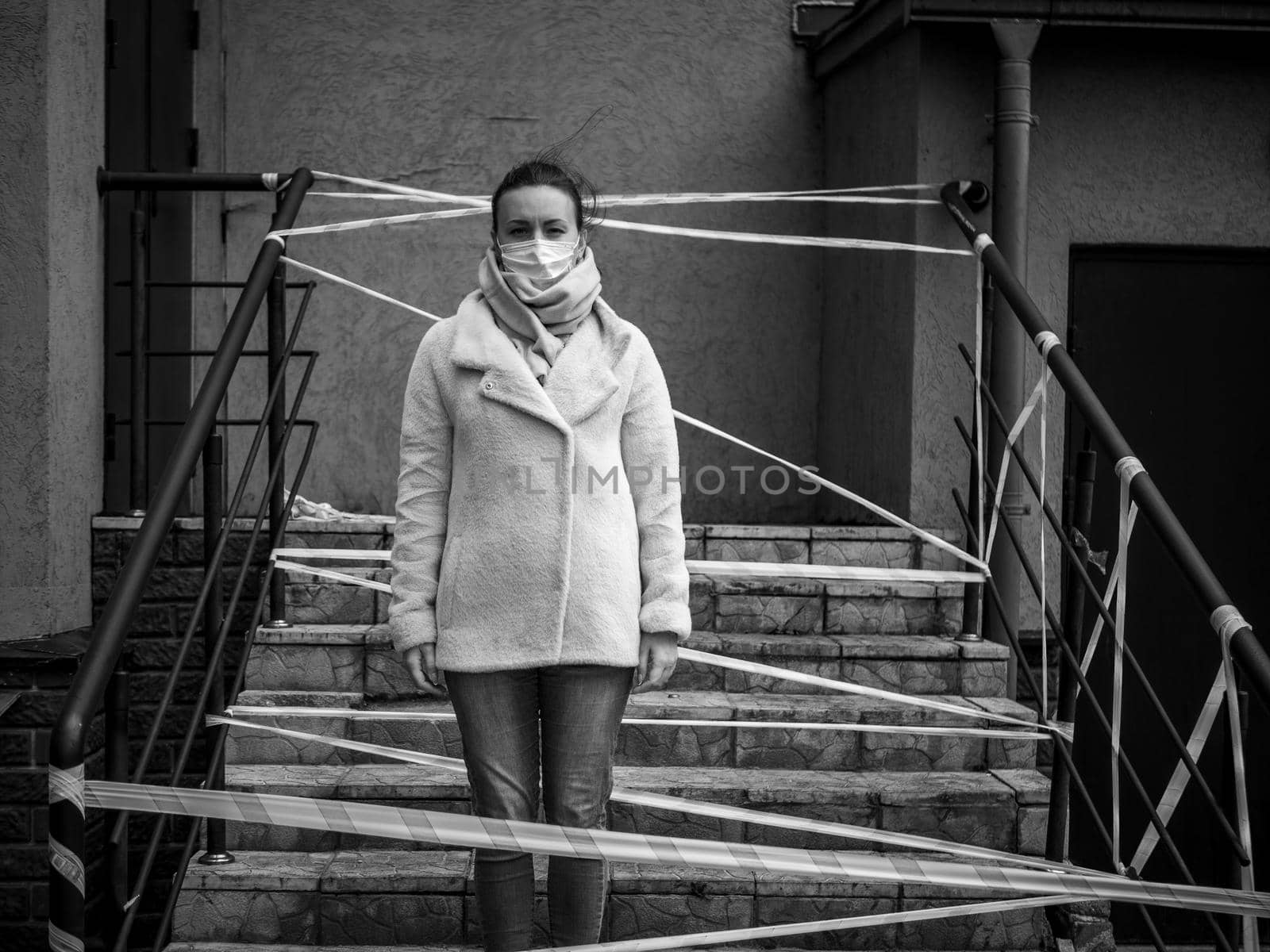 Photo of a girl in a mask. Standing on the street with danger warning tapes. isolated Covid-19 pandemic.