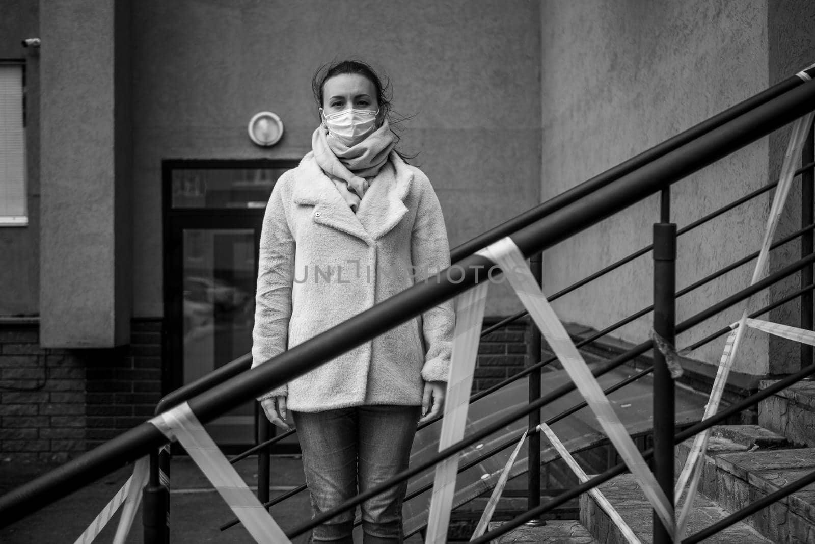 Photo of a girl in a mask. Standing on the street with danger warning tapes. isolated Covid-19 pandemic.