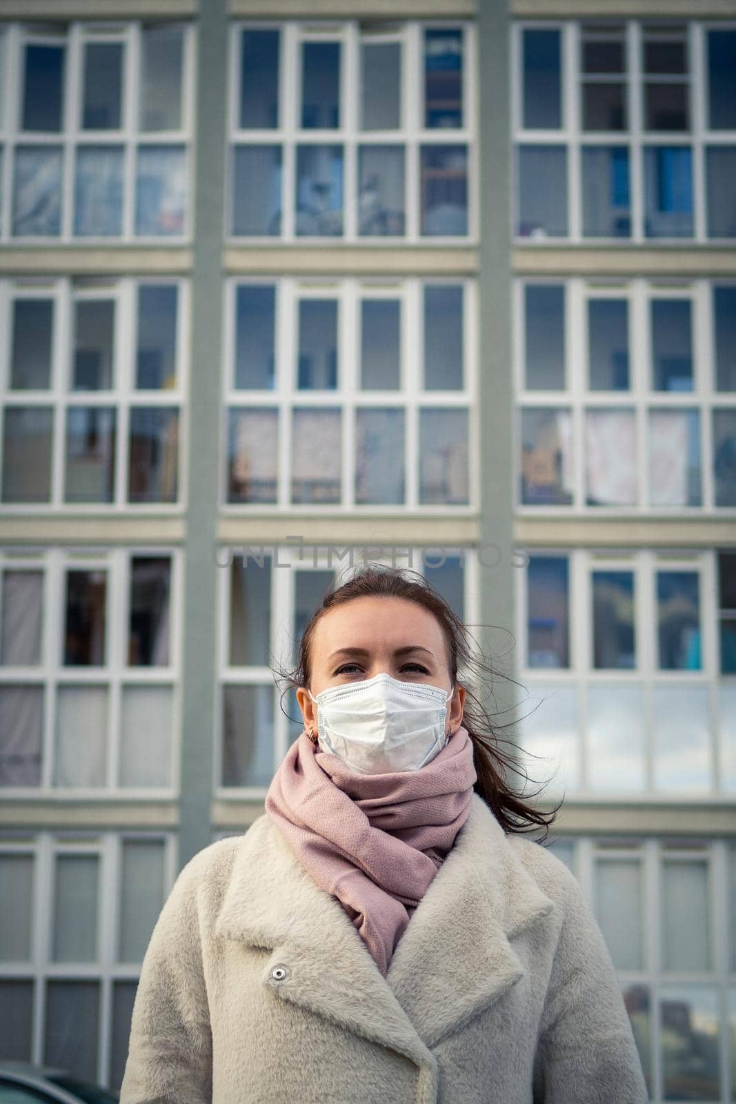 Shot of a girl in wearing face mask for protection, on the street. Against the background of a residential building with windows. lockdown Covid-19 pandemic.