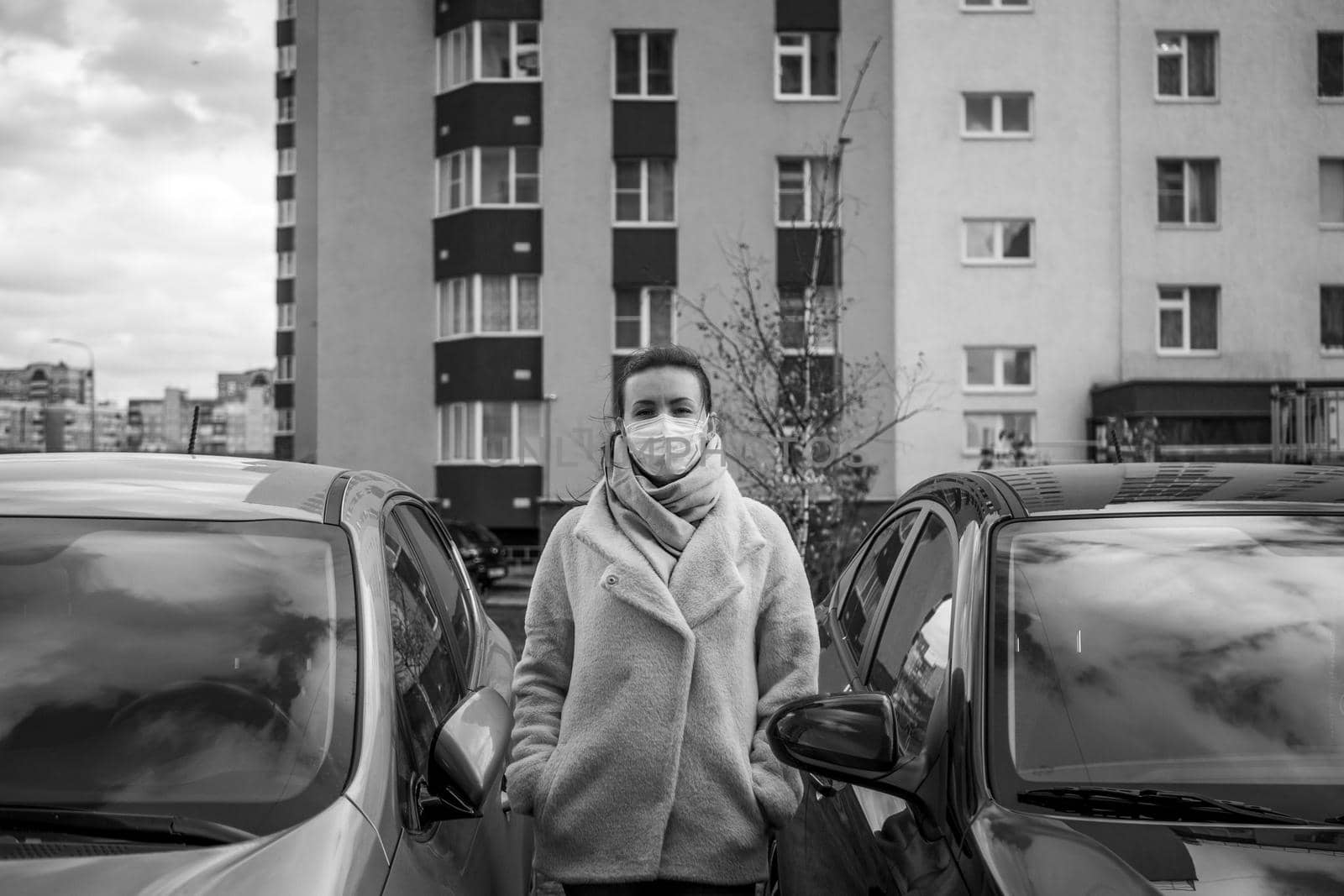 picture of a girl in a mask, on the street. Against the background of parked cars. isolated Covid-19 pandemic.