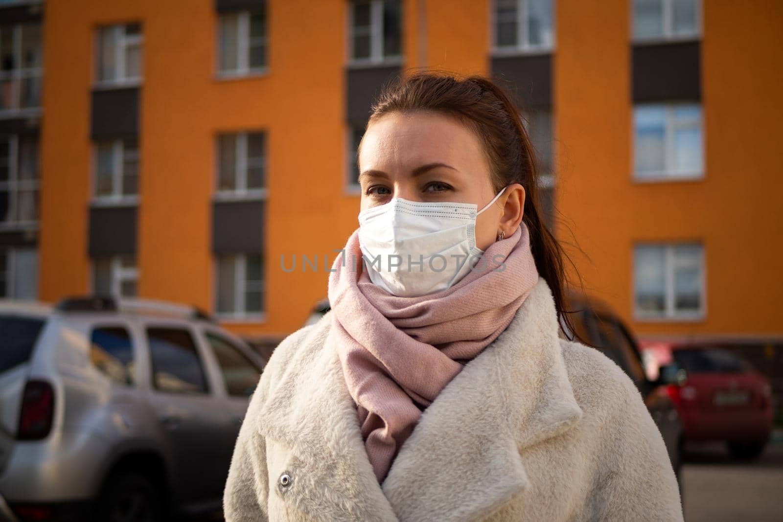 Shot of a girl in wearing face mask for protection, on the street. Against the background of a residential building with windows. lockdown Covid-19 pandemic.