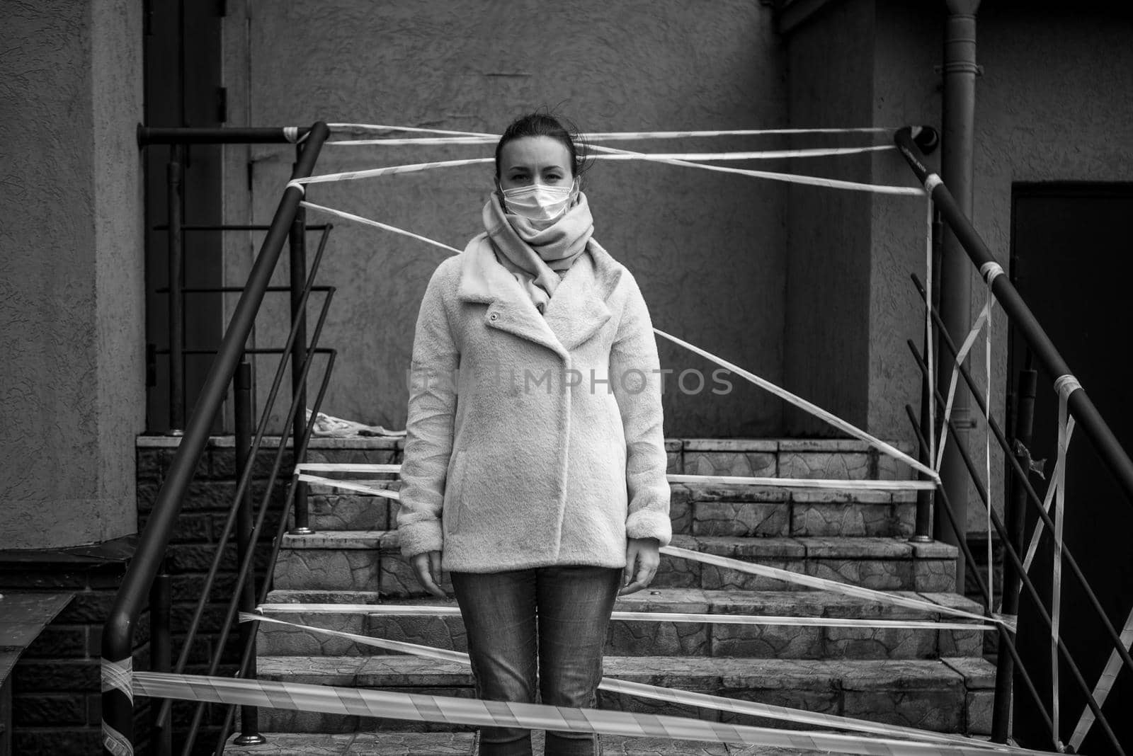 Photo of a girl in a mask. Standing on the street with danger warning tapes. isolated Covid-19 pandemic.