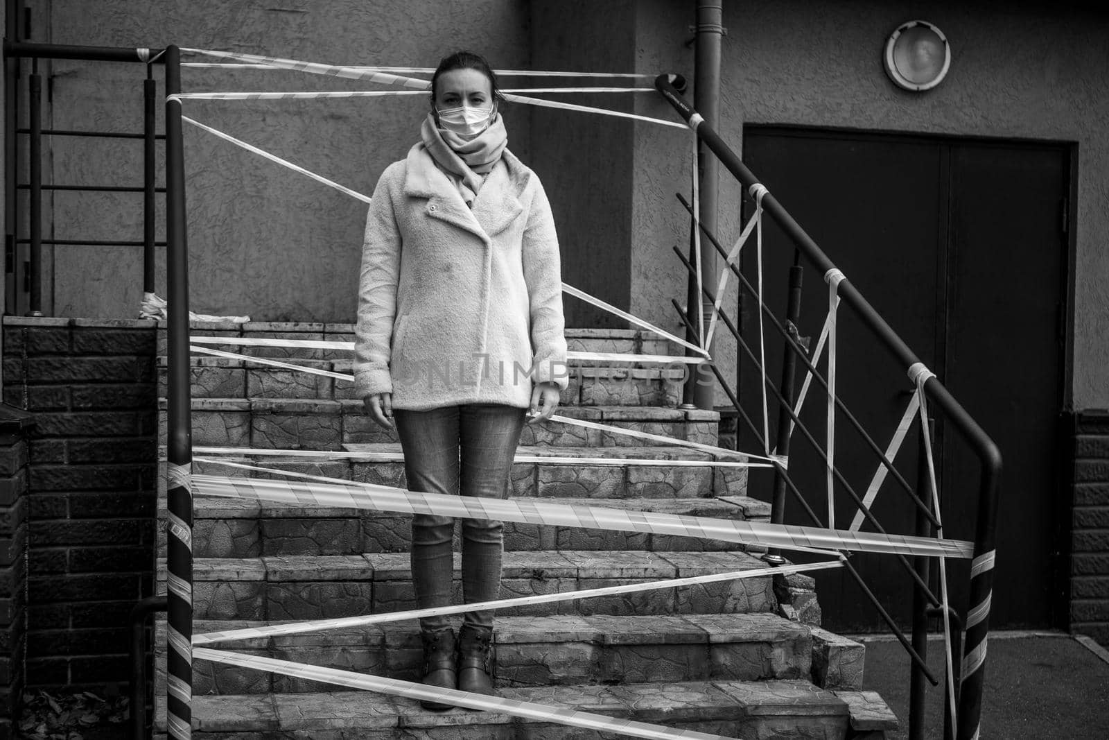 Photo of a girl in a mask. Standing on the street with danger warning tapes. isolated Covid-19 pandemic.