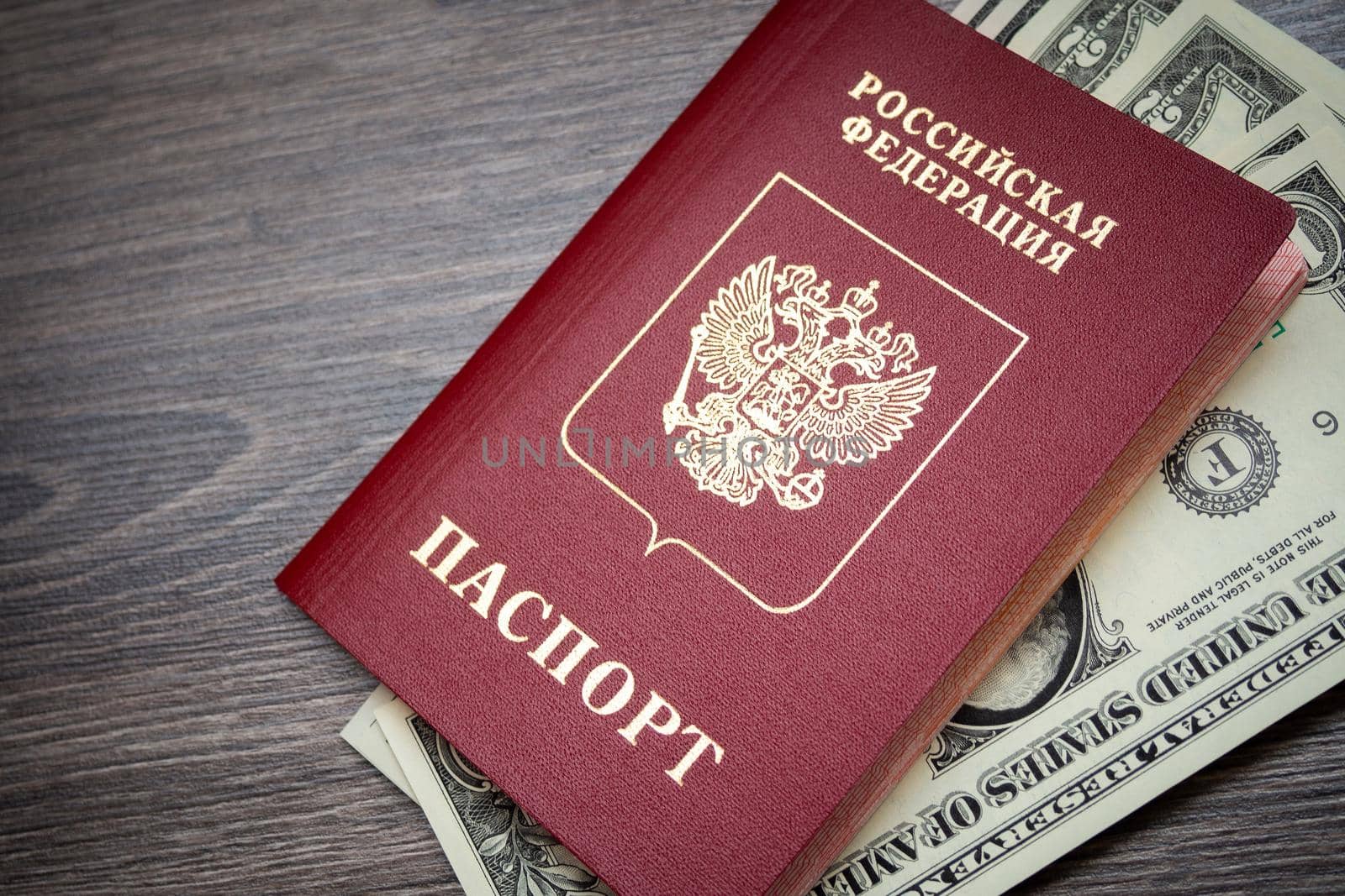 A foreign passport and dollars on a wooden background. by Evgenii_Leontev