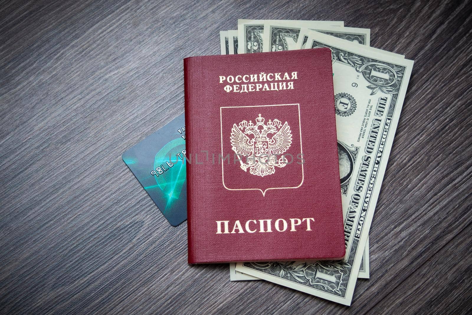 A foreign passport and dollars on a wooden background. Photos of documents and banknotes.