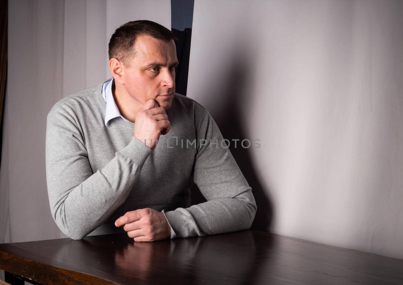 handsome man in a suit poses in an interior studio. looks at the camera