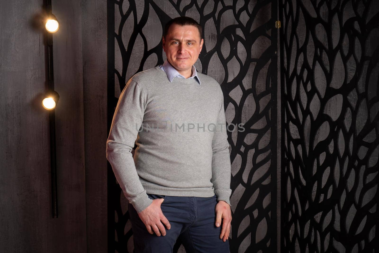 handsome man in a suit poses in an interior studio. looks at the camera