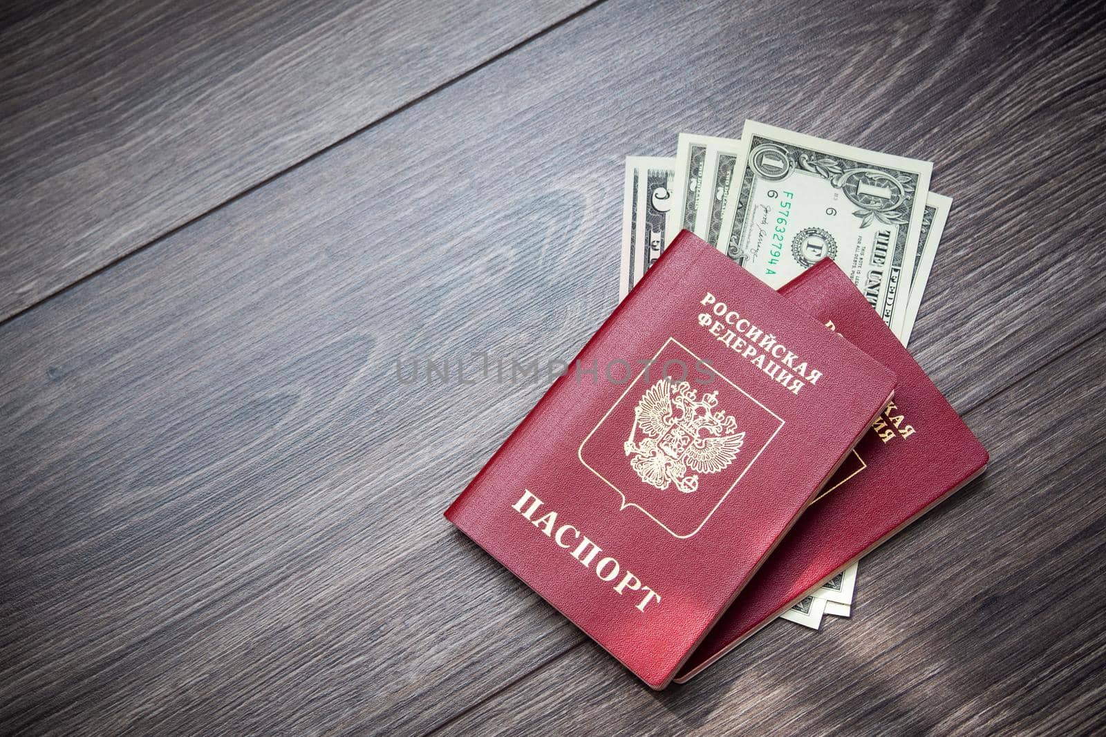 A foreign passport and dollars on a wooden background. by Evgenii_Leontev