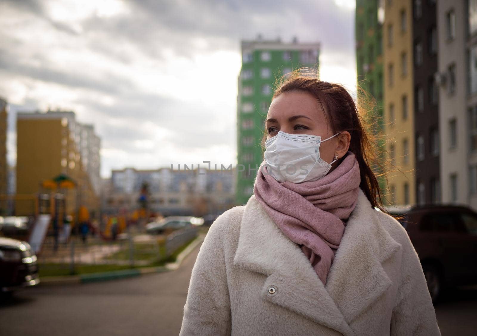 Shot of a girl in wearing face mask for protection, on the street. Against the background of a residential building with windows. lockdown Covid-19 pandemic.