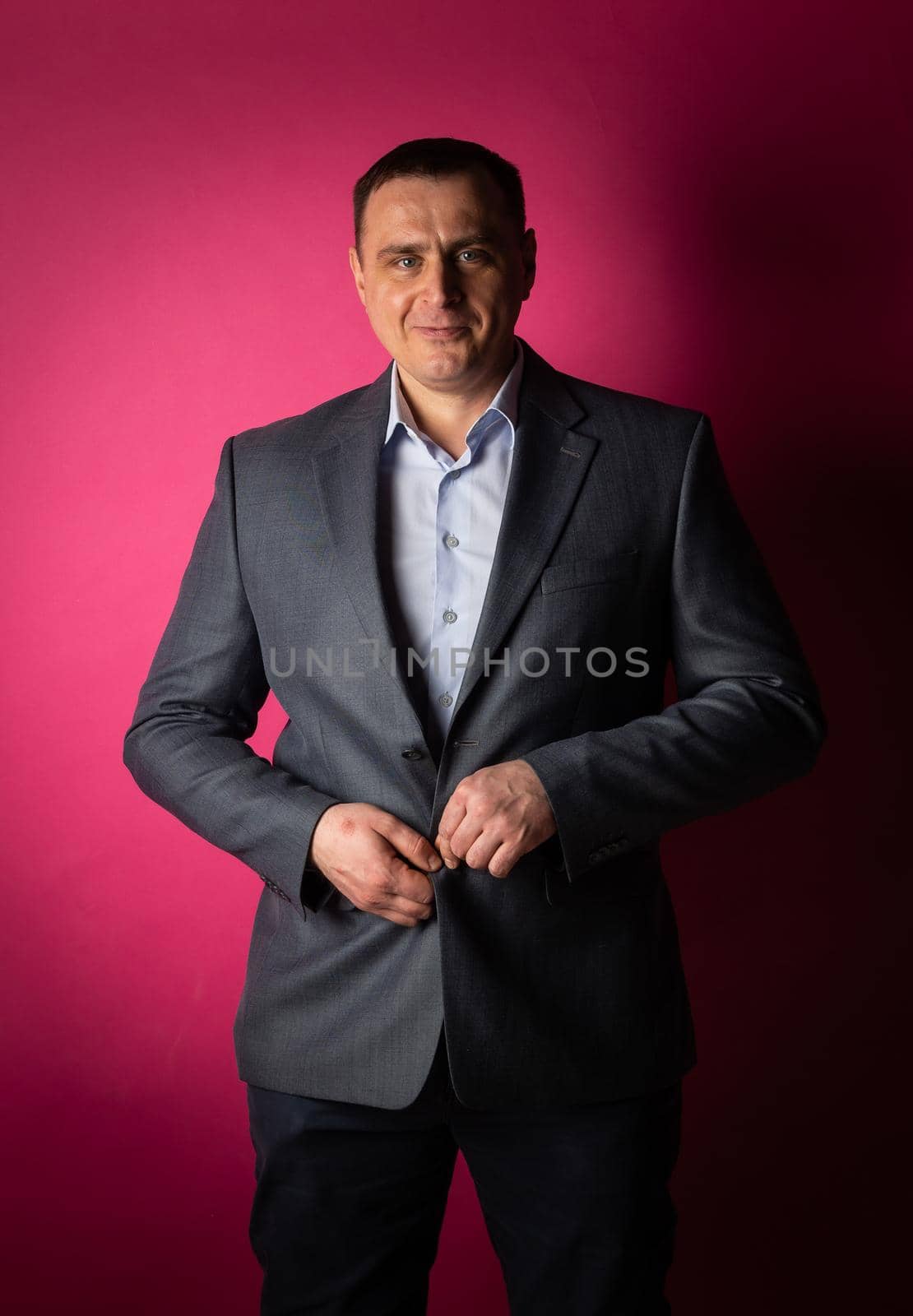 handsome businessman in a suit looks at the camera. isolated on a pink background