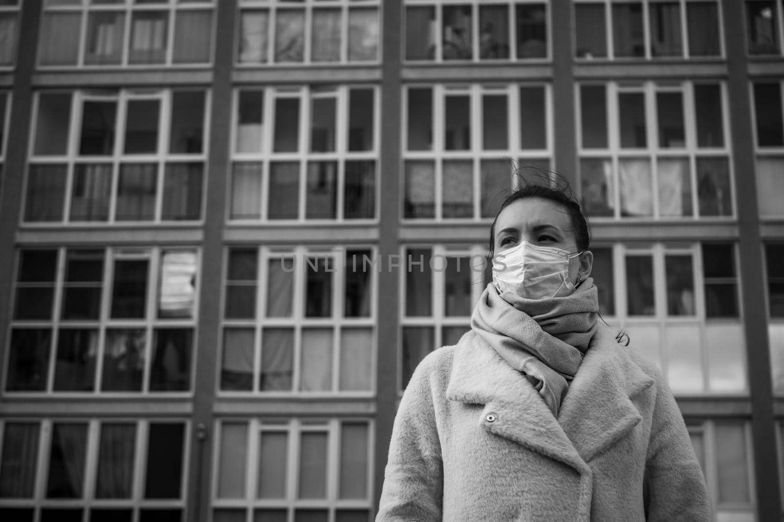 Shot of a girl in wearing face mask for protection, on the street. Against the background of a residential building with windows. lockdown Covid-19 pandemic.