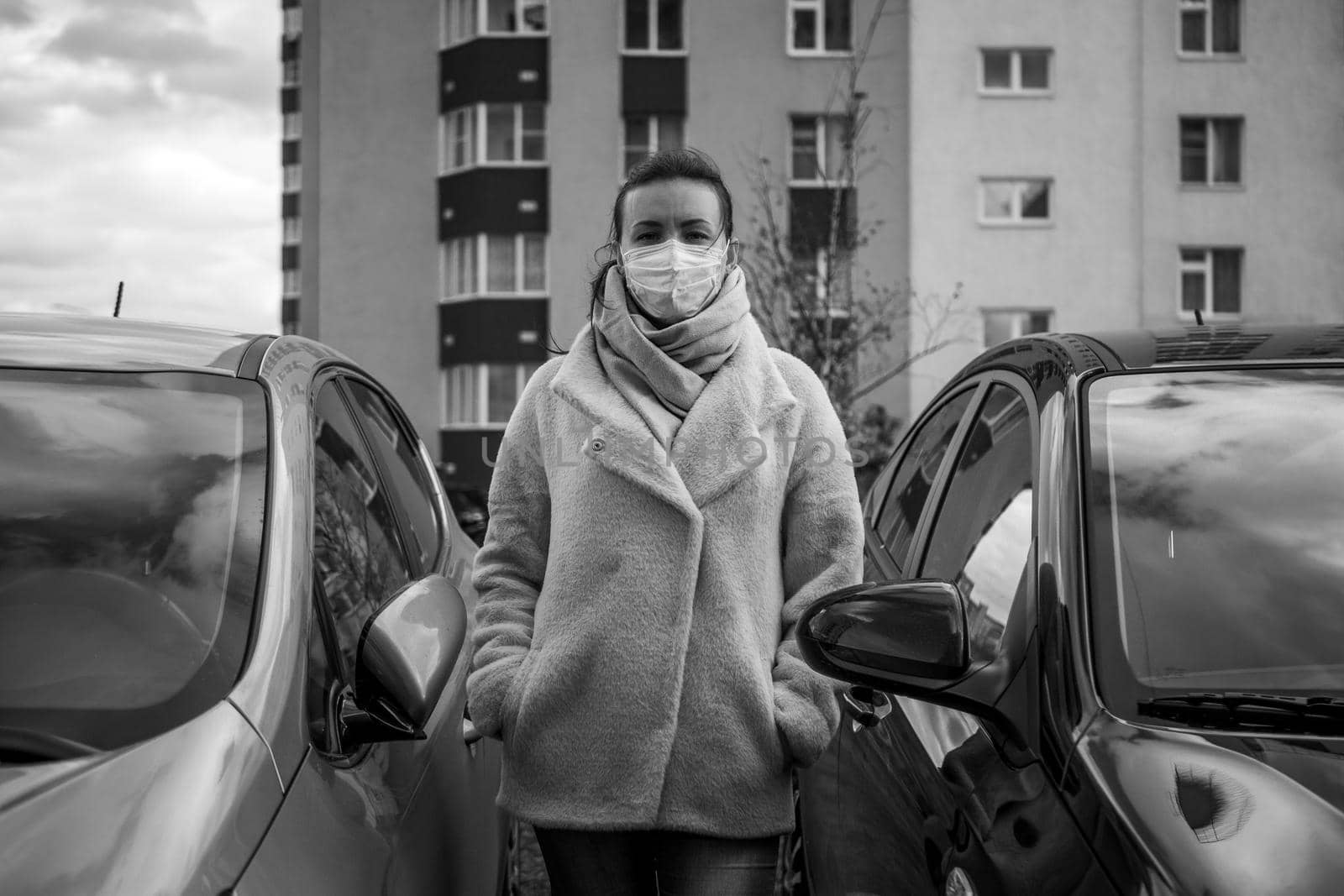 picture of a girl in a mask, on the street. Against the background of parked cars. isolated Covid-19 pandemic.