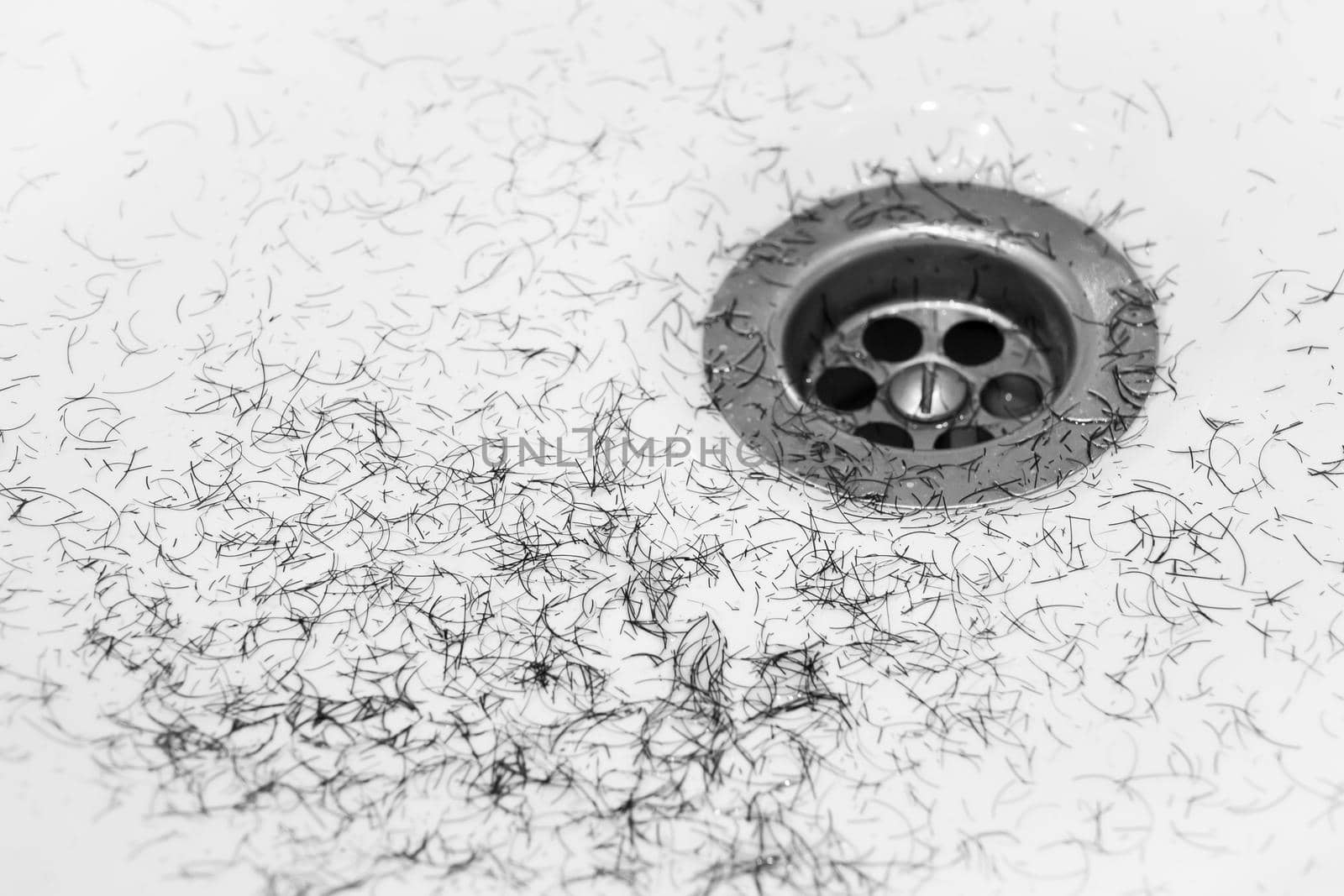 Dirty wash hand basin showing grungy drain with bits of hair.