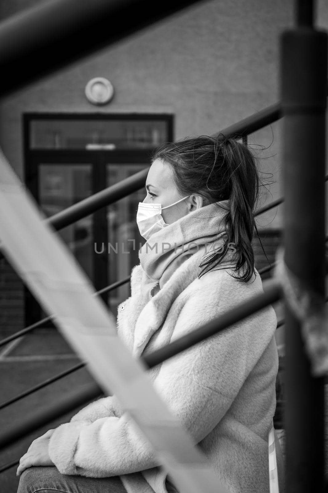 Photo of a girl in a mask. Sitting on the street with danger warning tapes. isolated Covid-19 pandemic.