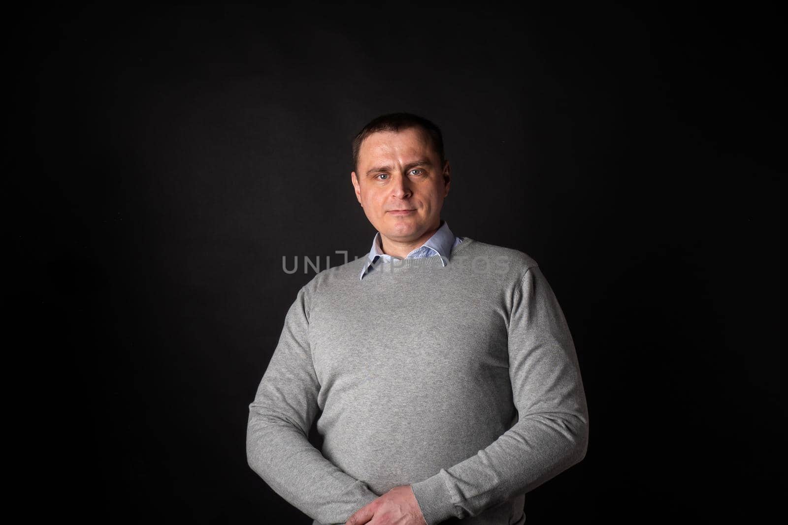 handsome businessman in a suit looks at the camera. isolated on a black background