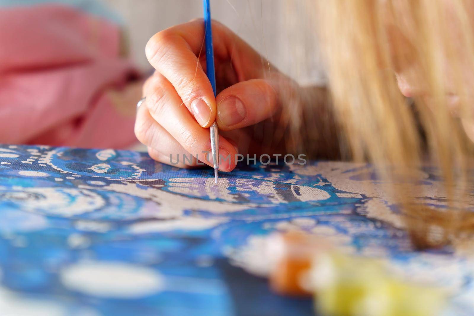 Close up of a young woman artist hand painting a picture by numbers. Creativity and art relieve stress. Hobby at home