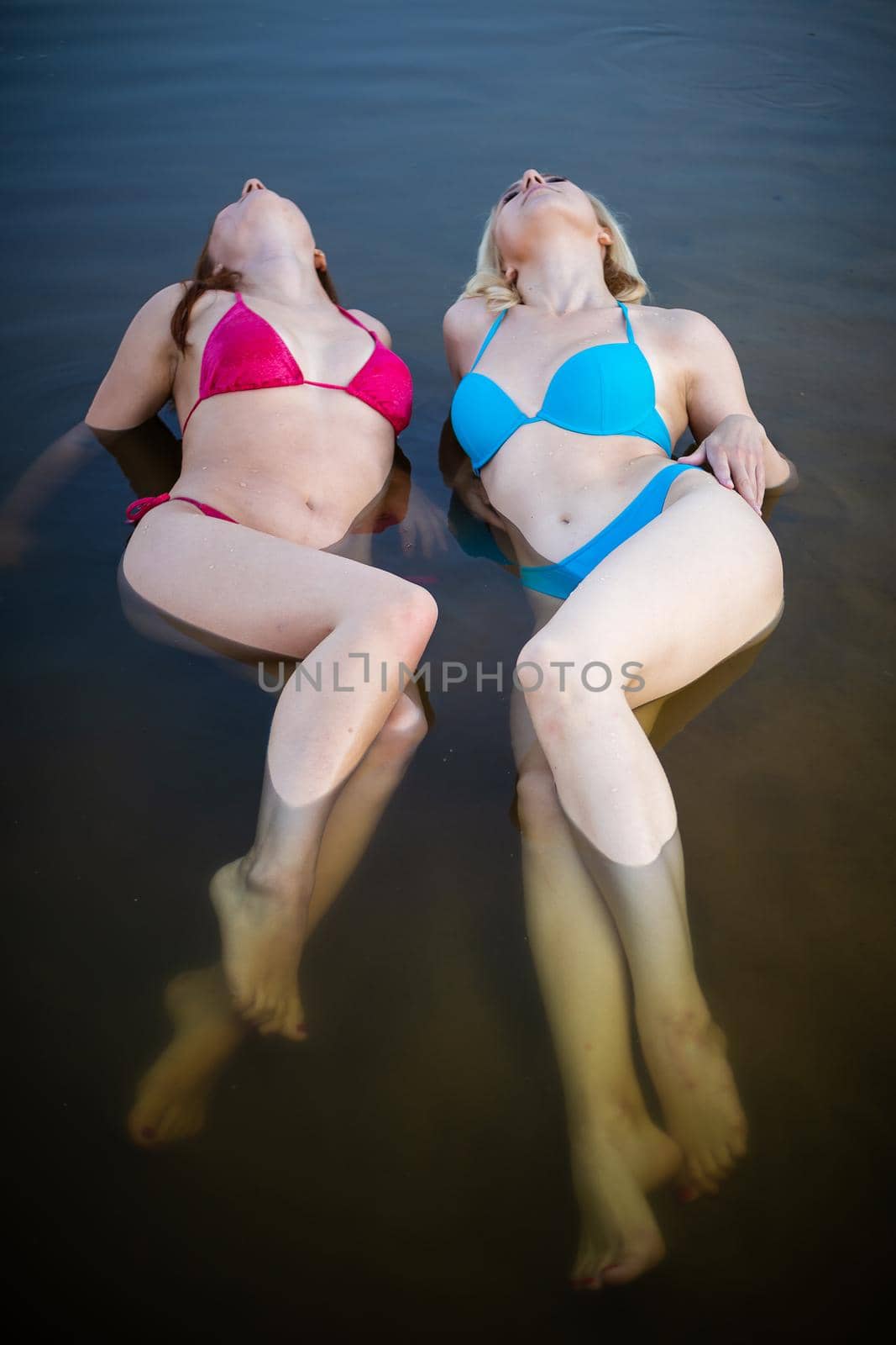 Front view of two young women with beautiful bodies in bikinis. by Evgenii_Leontev
