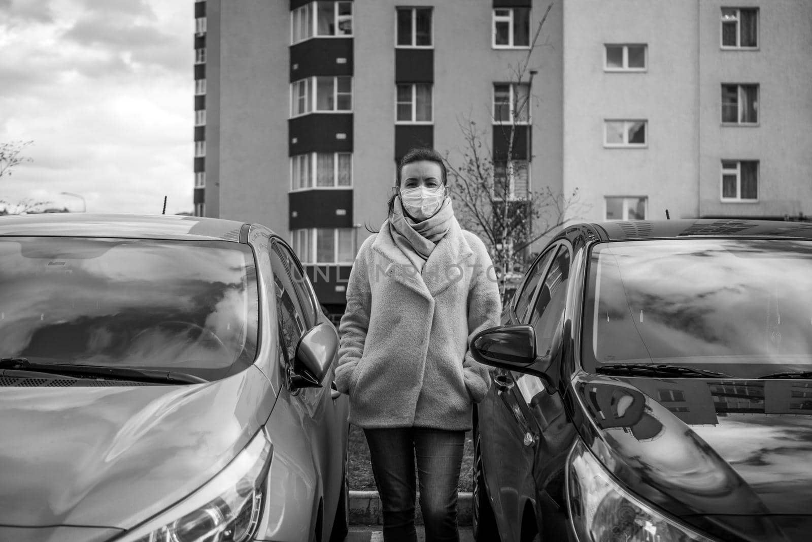 picture of a girl in a mask, on the street. Against the background of parked cars. isolated Covid-19 pandemic.