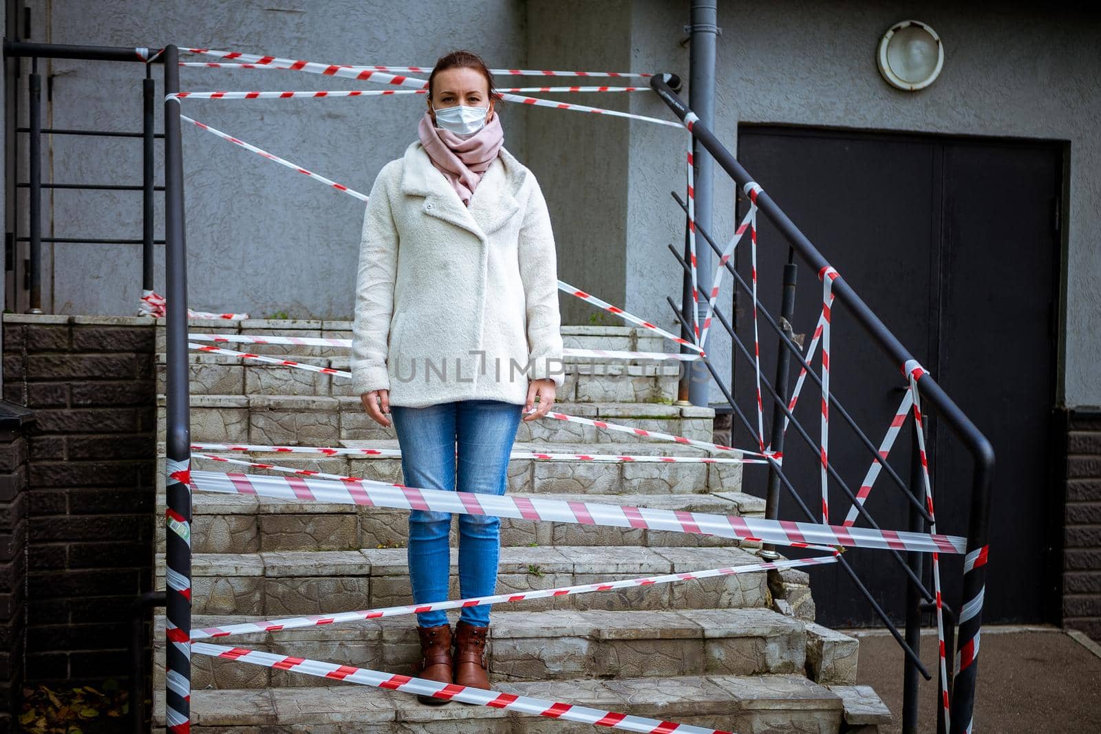 Photo of a girl in a mask. Standing on the street with danger warning tapes. isolated Covid-19 pandemic.