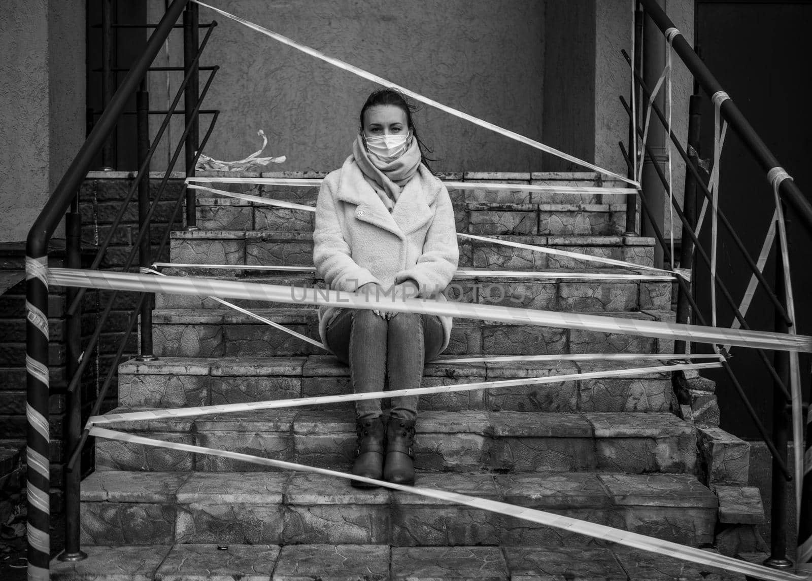 Photo of a girl in a mask. Sitting on the street with danger warning tapes. isolated Covid-19 pandemic.