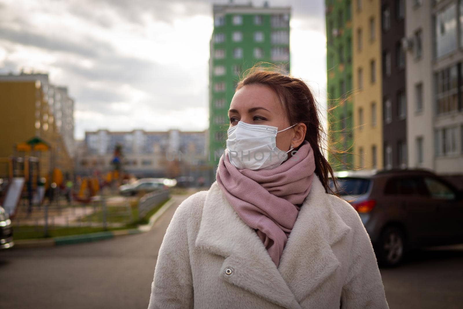 Shot of a girl in wearing face mask for protection, on the street. Against the background of a residential building with windows. lockdown Covid-19 pandemic.