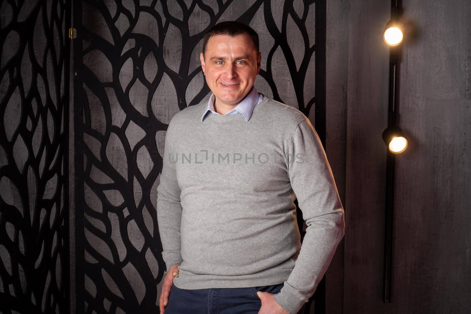 handsome man in a suit poses in an interior studio. looks at the camera