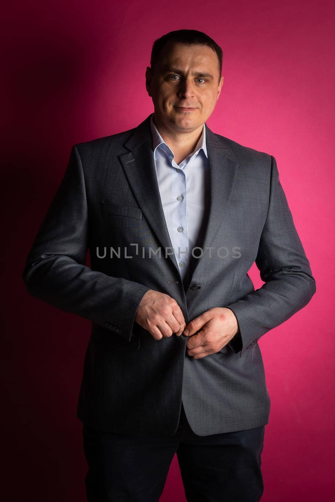 handsome businessman in a suit looks at the camera. isolated on a pink background