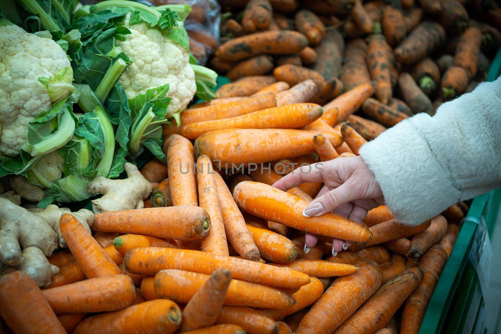 A woman's hand, buying groceries at the supermarket. Vegetables and fruits in a large assortment.