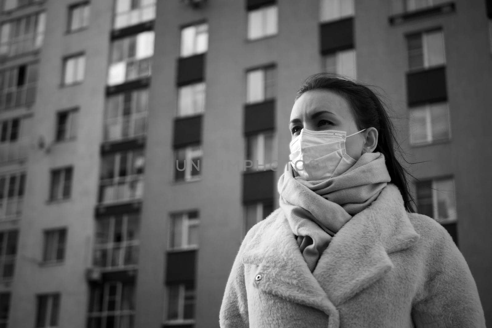 Shot of a girl in wearing face mask for protection, on the street. Against the background of a residential building with windows. lockdown Covid-19 pandemic.