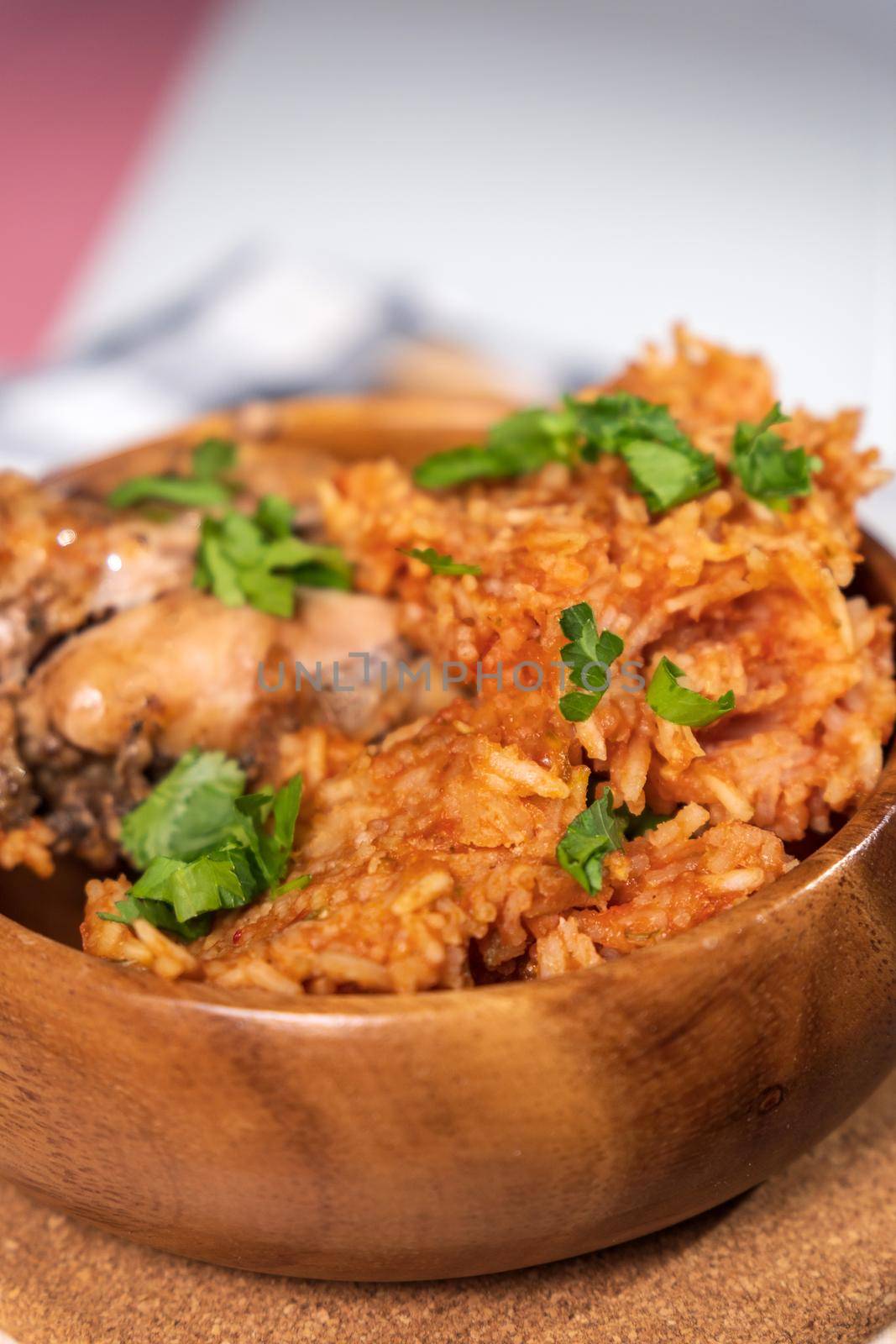 Bowl of east African Jollof Rice garnished with pieces of roasted chicken. Vertical photo by darksoul72