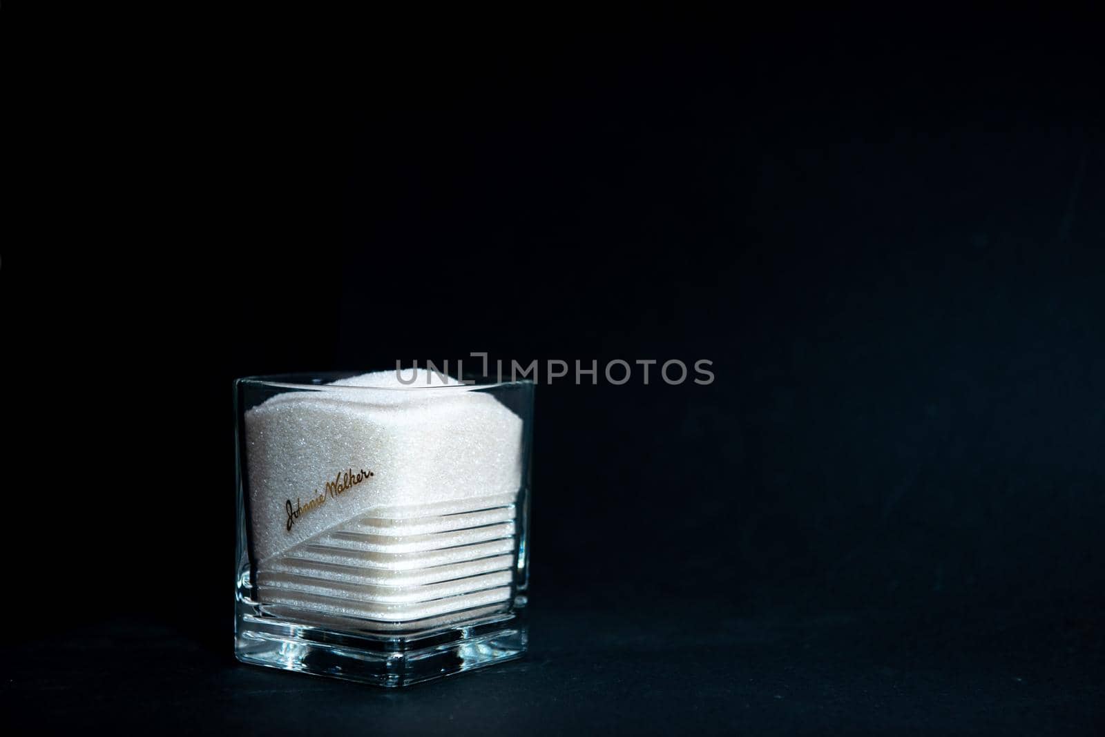 sugar in a transparent glass with a corrugated face on a black background