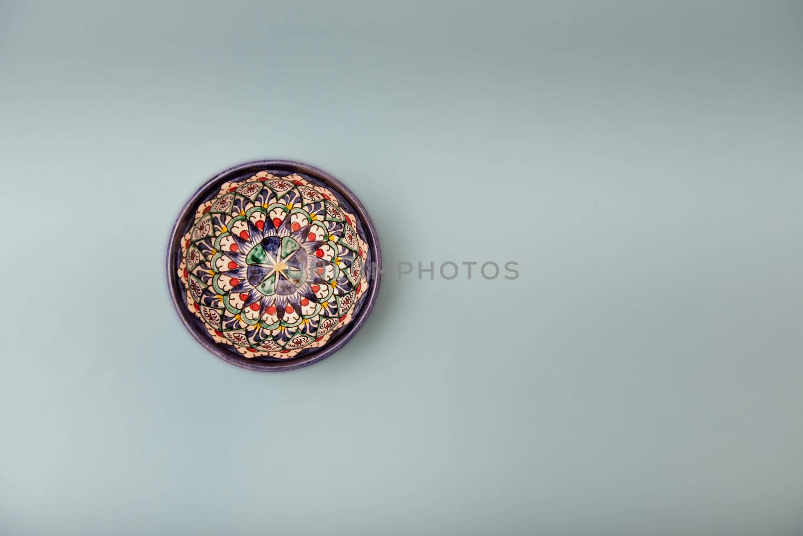 Ethnic Uzbek ceramic tableware on the gray background. Decorative ceramic cup with traditional uzbekistan ornament.