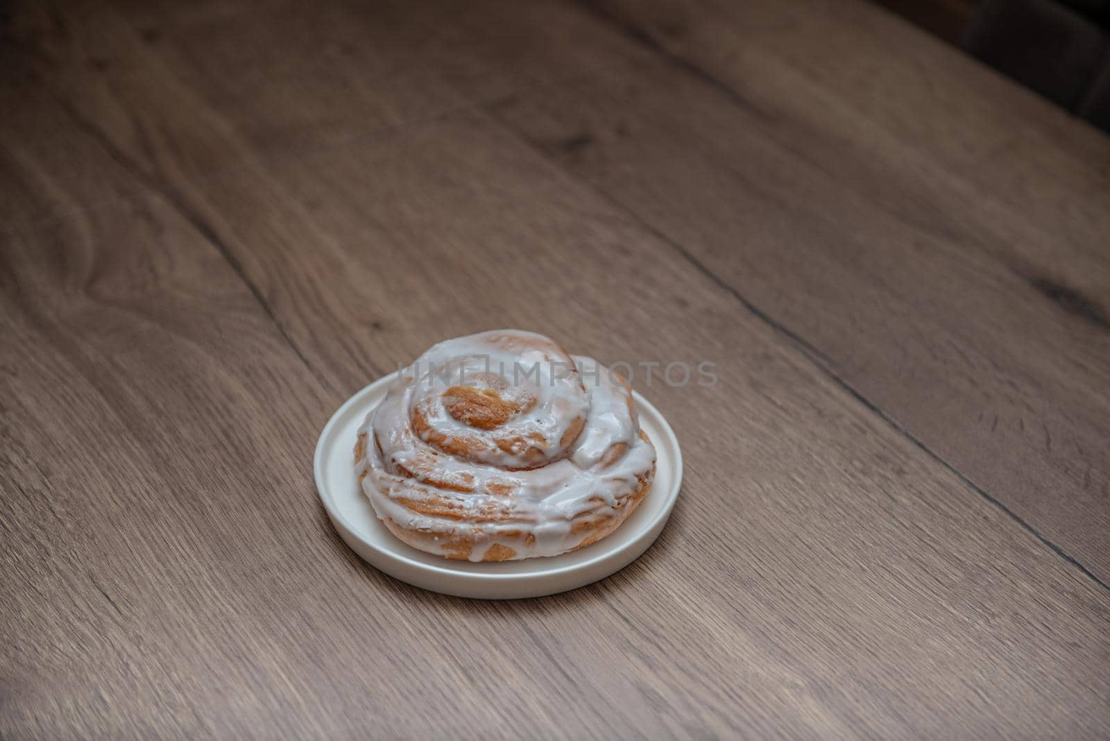 Snail buns on a white plate and wooden background. Cinnamon rolls. Bakery products. by marynkin