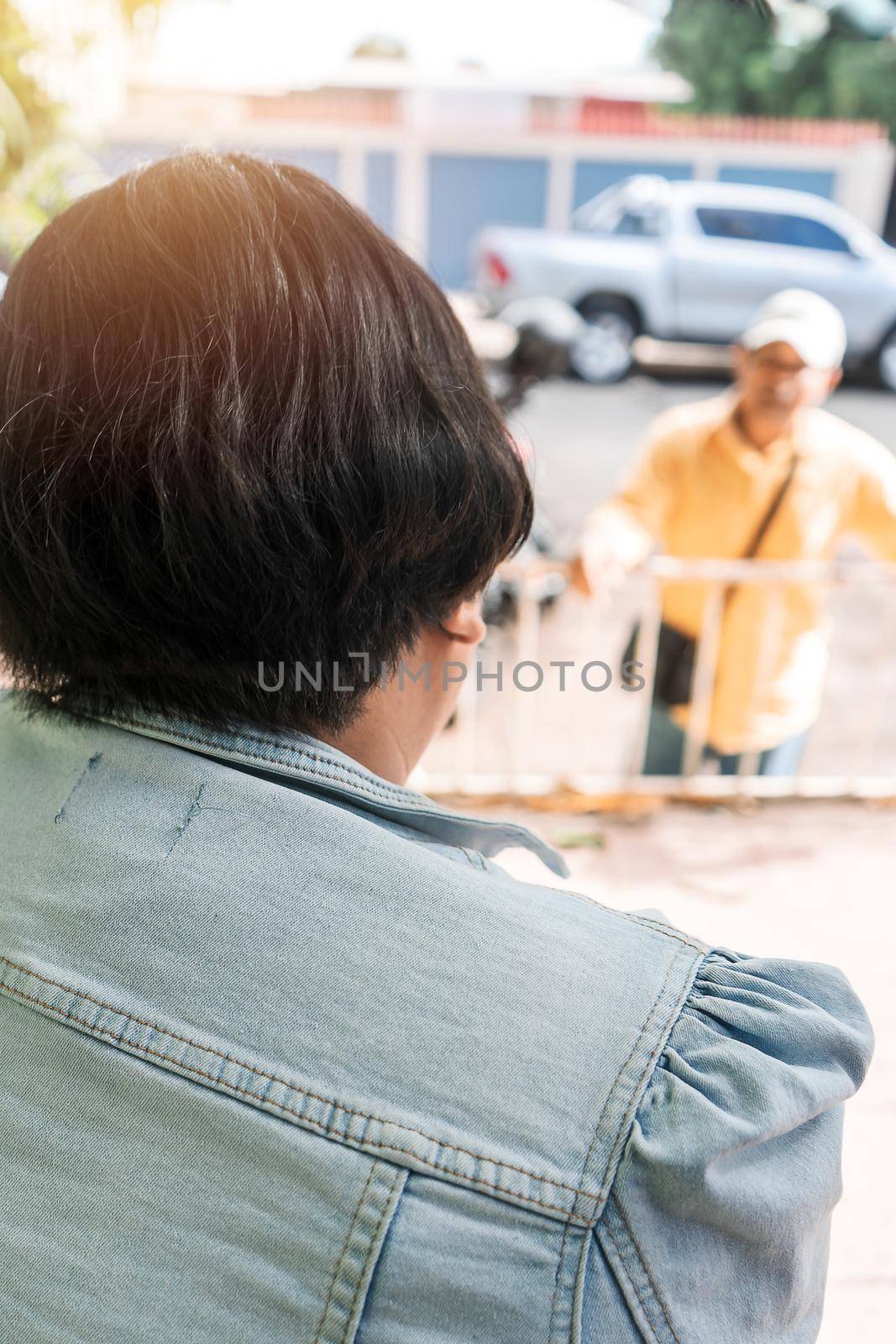 Vertical photo of a Latin woman talking and gossiping with a man from afar on the street.