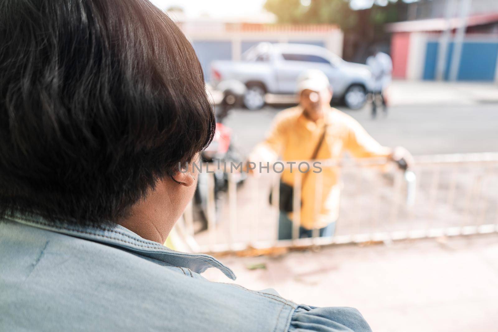Latin woman talking and gossiping with a man from afar on the street.
